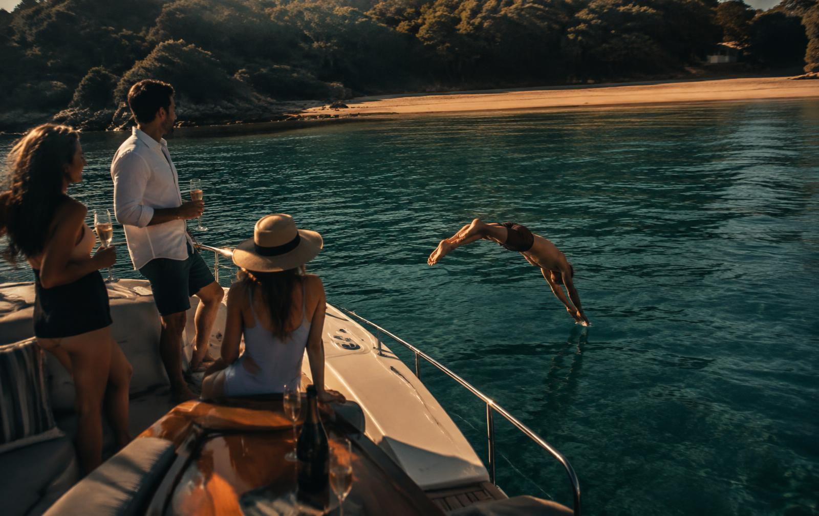 Friends swimming off a boat in an empty harbour bay on a weekday